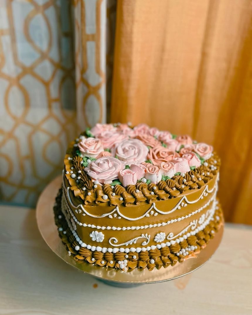 Pastel de dos pisos con rosas de crema y detalles dorados